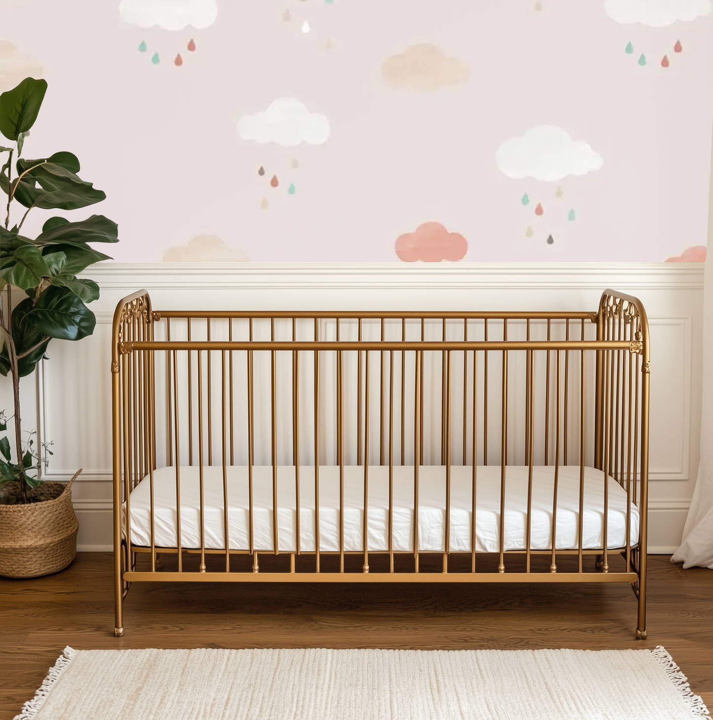 A nursery room with the Pink Clouds Mural on the wall, featuring a gold crib in the foreground and a plant to the left.