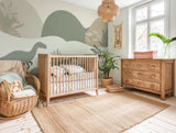 Dinosaur nursery mural wallpaper featuring soft-coloured dinosaurs, muted hills, and mountains, styled in a kids nursery with neutral wooden crib.