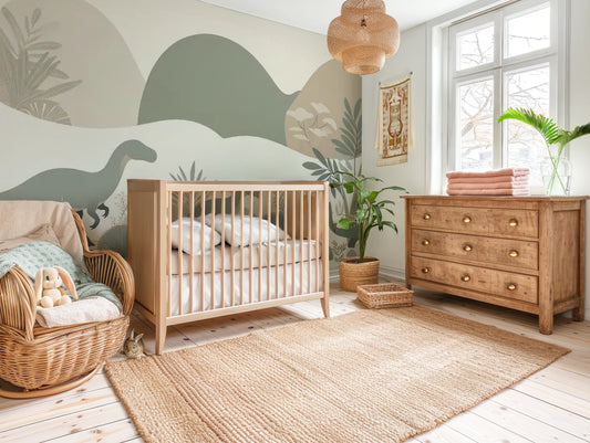Dinosaur nursery mural wallpaper featuring soft-coloured dinosaurs, muted hills, and mountains, styled in a kids nursery with neutral wooden crib.