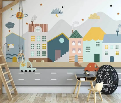 A colorful mural of a mini town with various buildings, a road, and decorative elements like clouds and stars, applied on a wall in a room with wooden furniture and a chalkboard.